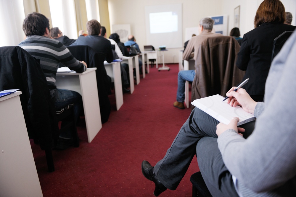 Grupo de pessoas tendo aula em pequena sala de conferência